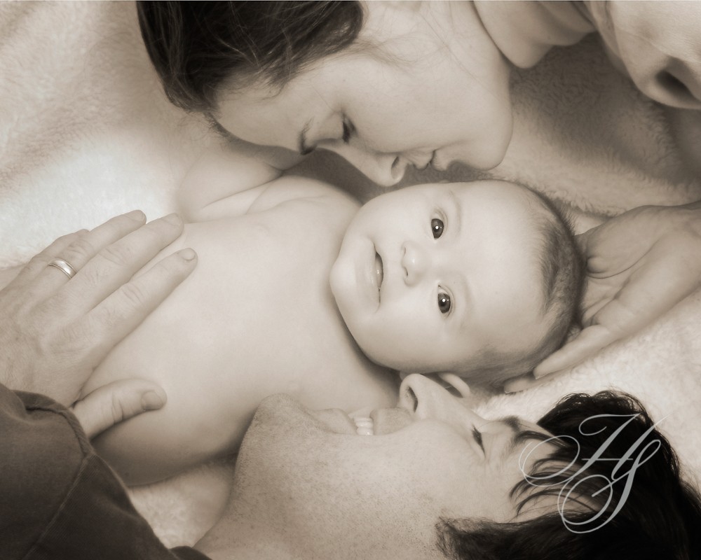 A baby is being held by two men.
