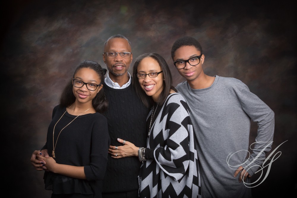 A family posing for a picture in front of a brown background.