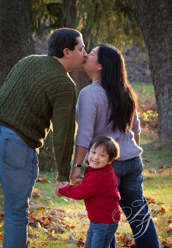 A man and woman kissing while holding hands with a child.