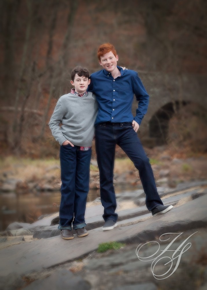 Two boys posing for a picture in front of a river.