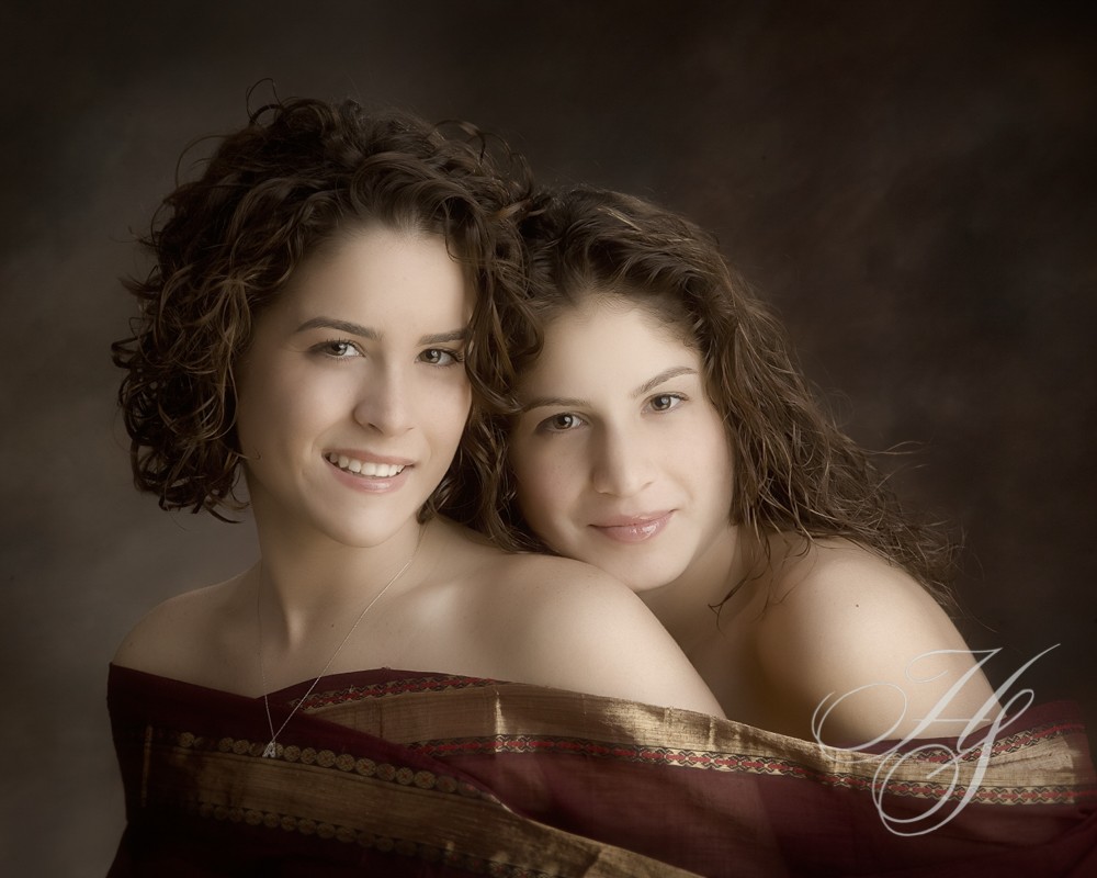 Two women posing for a picture in front of a wall.