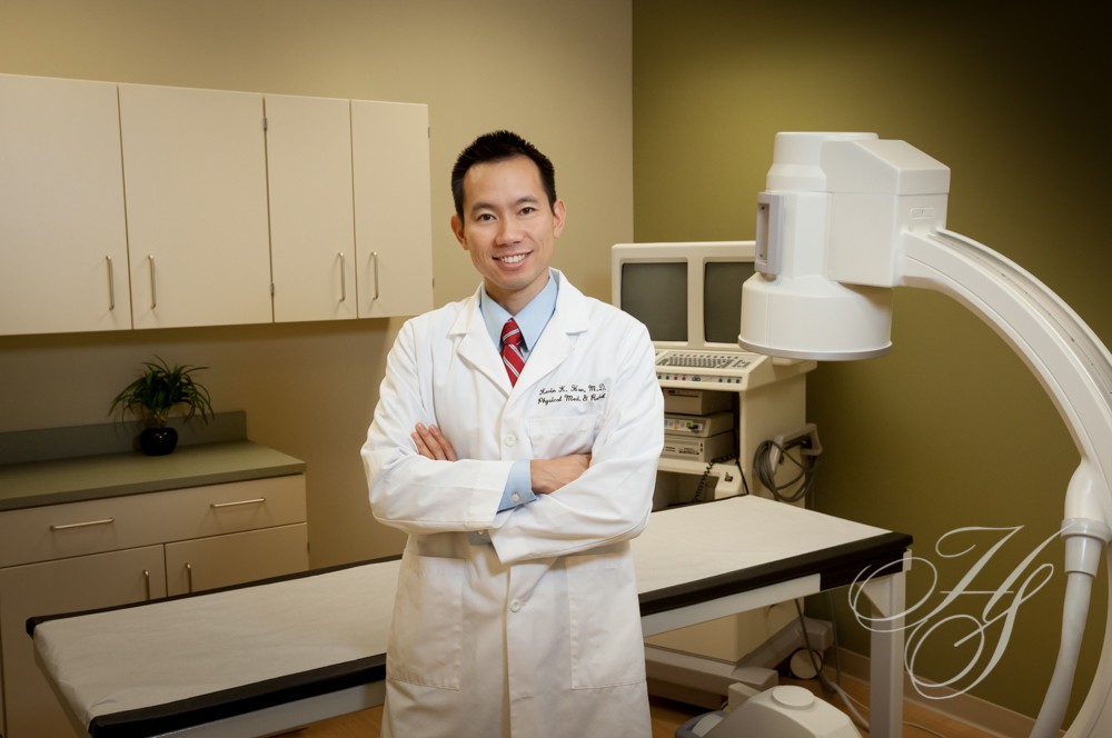 A man in white lab coat standing next to a table.