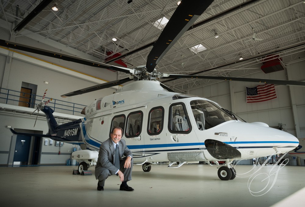 A man kneeling in front of a helicopter.
