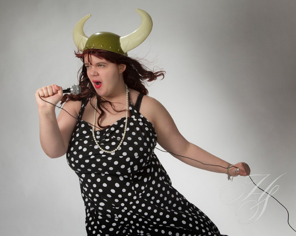 A woman wearing a green hat and holding a stick.