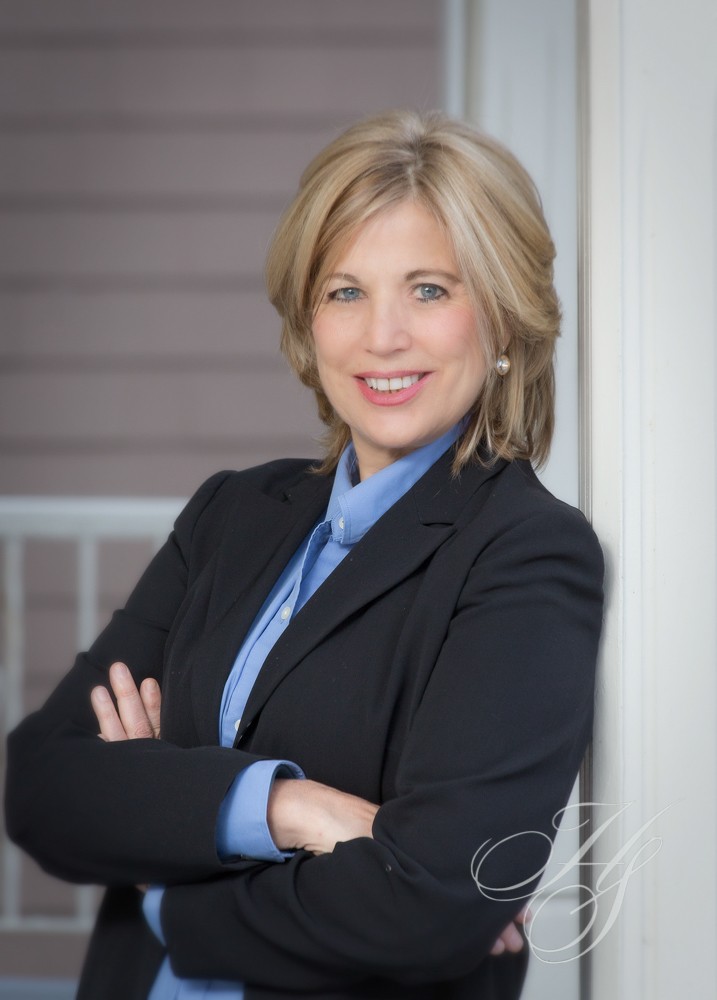 A woman in business attire with her arms crossed.