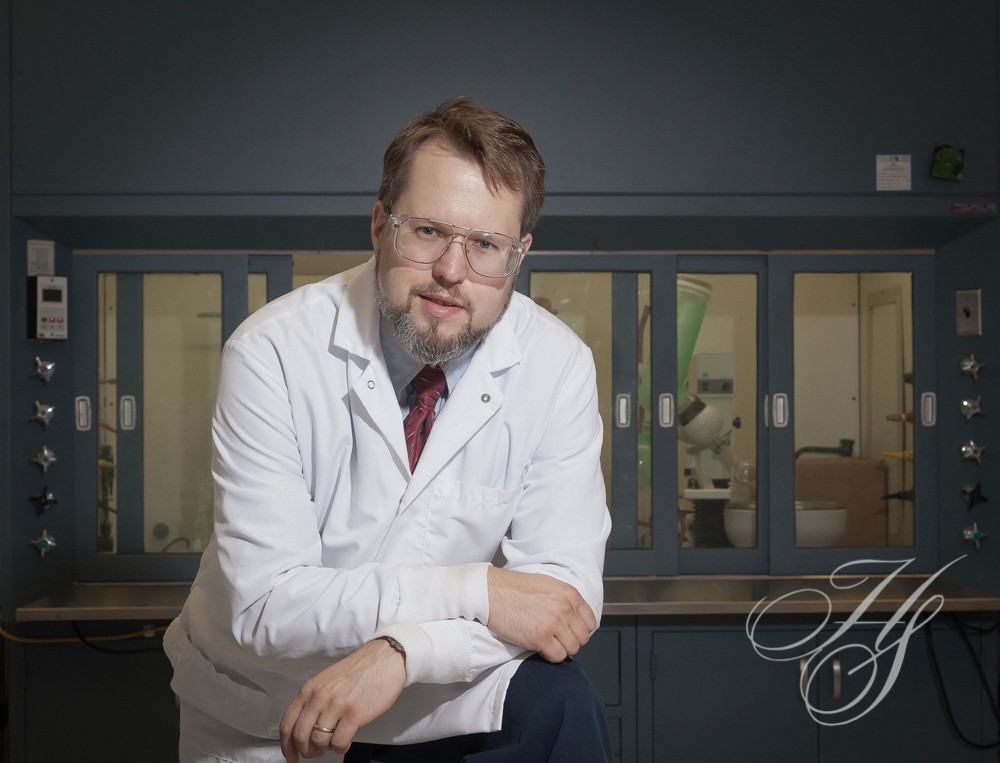 A man in white lab coat sitting on top of a chair.