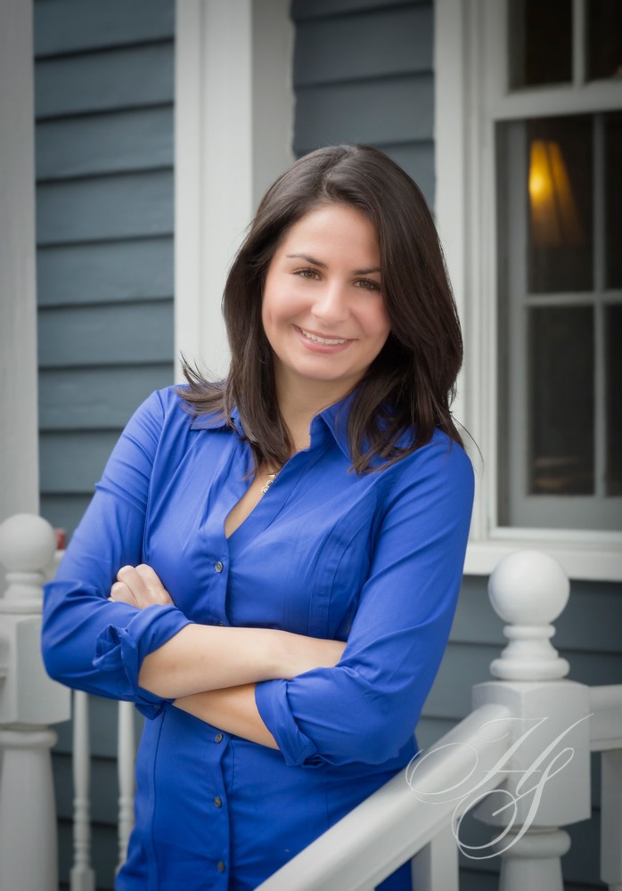 A woman standing in front of a house with her arms crossed.
