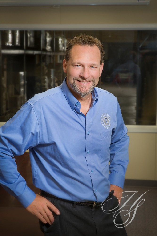 A man in blue shirt standing next to a window.