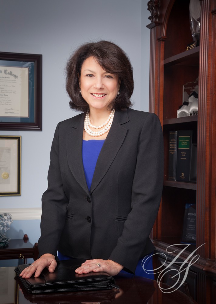 A woman in a suit standing next to a desk.
