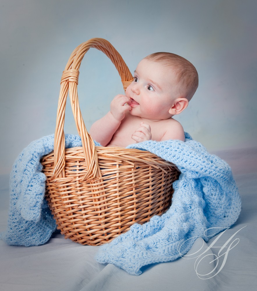 A baby in a basket with blue blanket