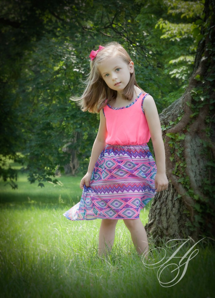 A little girl in a pink top and purple skirt