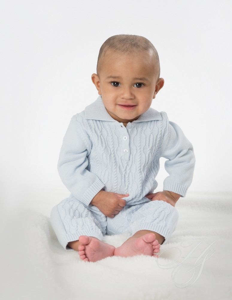 A baby sitting on the ground wearing pajamas.