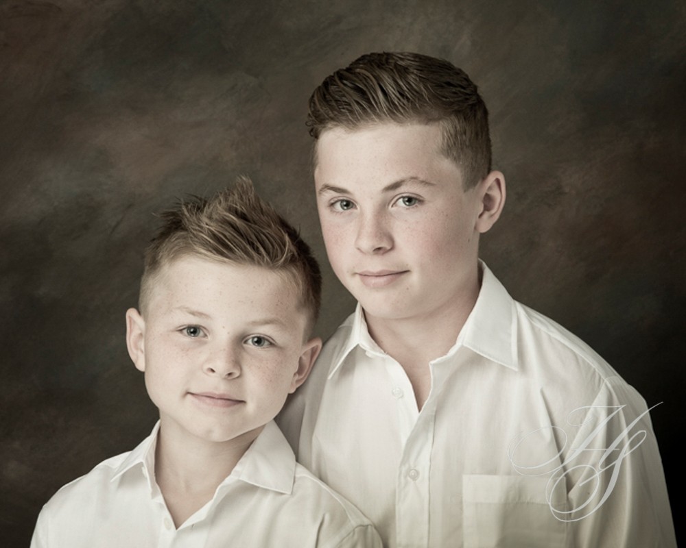 Two boys in white shirts posing for a picture.