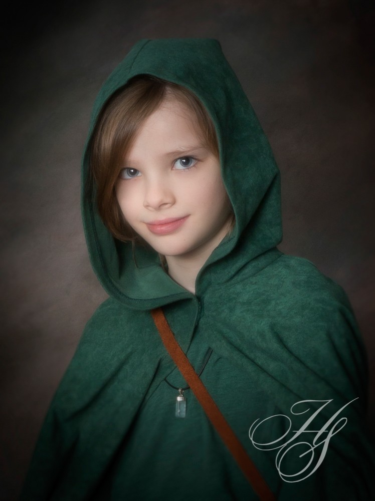 A young girl wearing a green hooded cape.