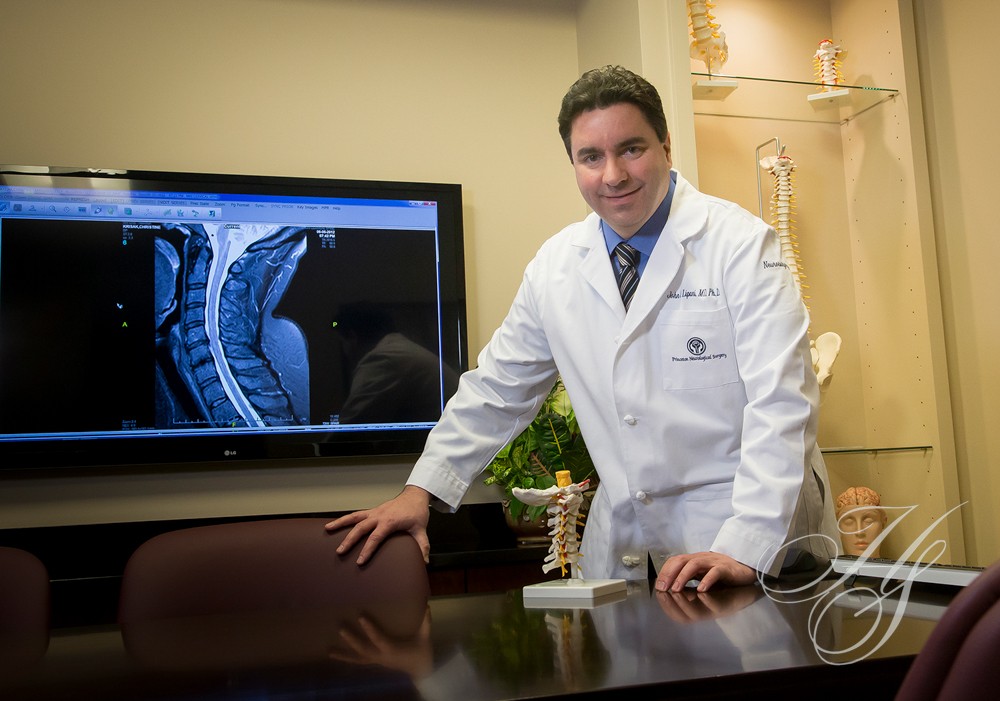 A man in white lab coat standing next to a table.