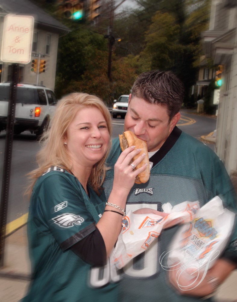 A man and woman eating hot dogs on the street.
