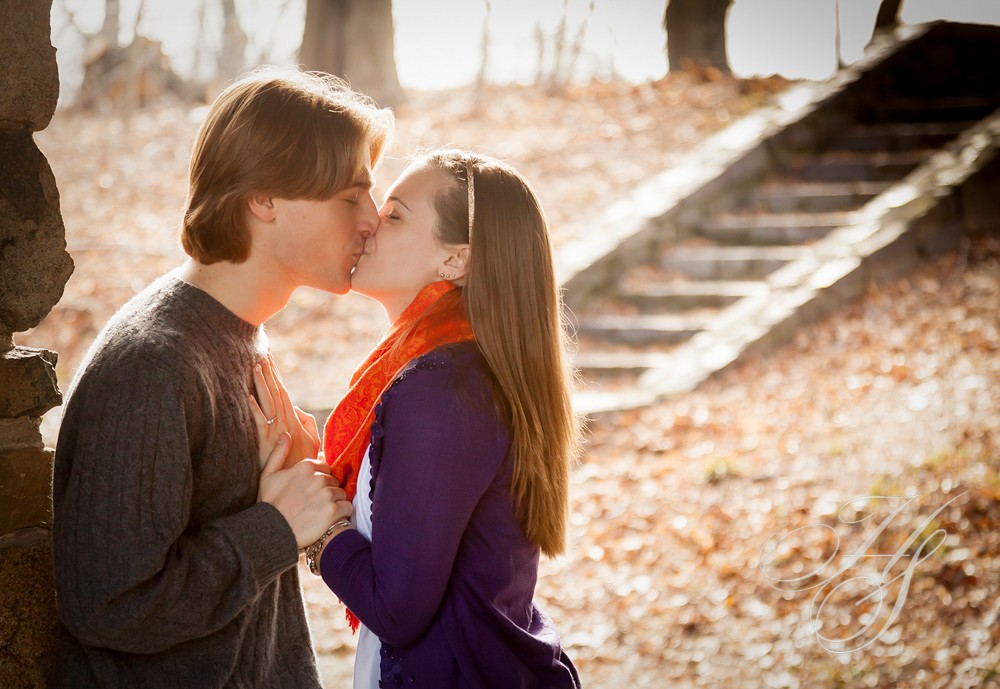 A man and woman kissing in the fall leaves.