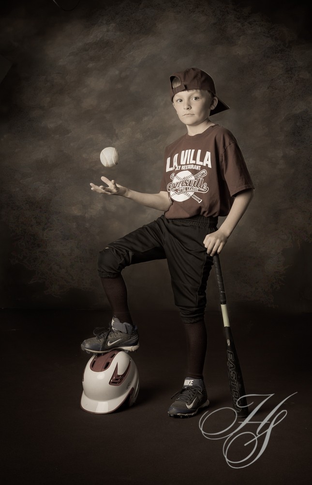 A boy is holding a ball and wearing baseball gear.