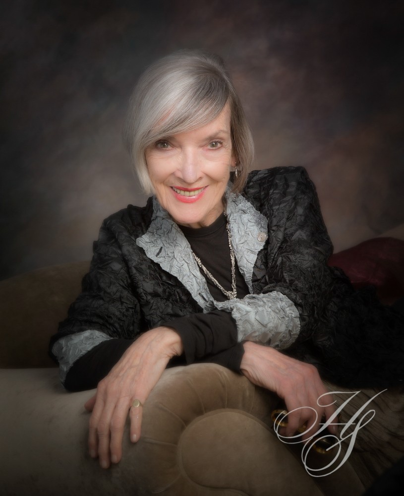 A woman with gray hair sitting on top of a couch.