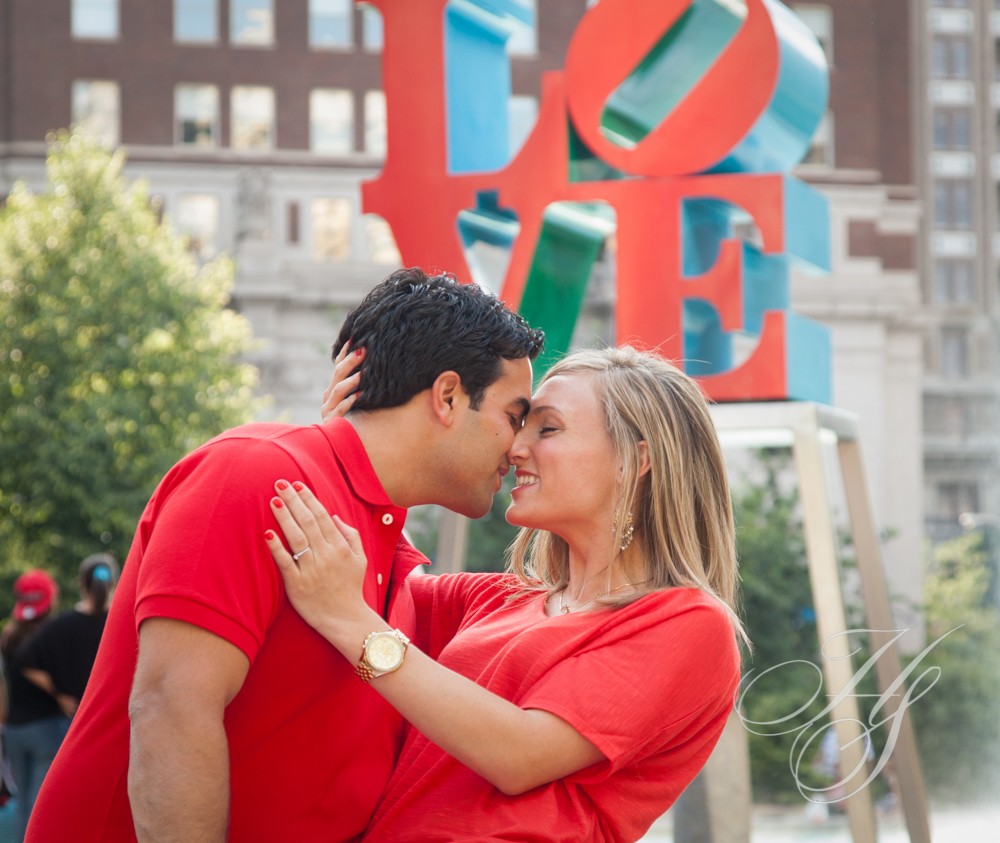 A man and woman kissing in front of the love sign.