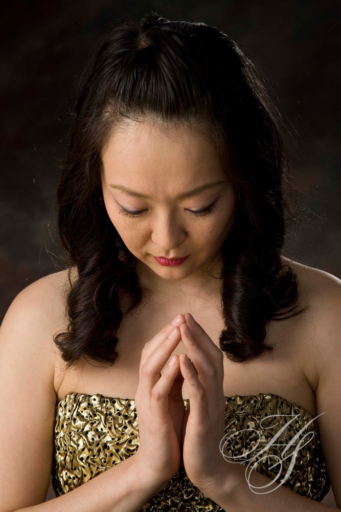 A woman in gold dress holding her hands together.