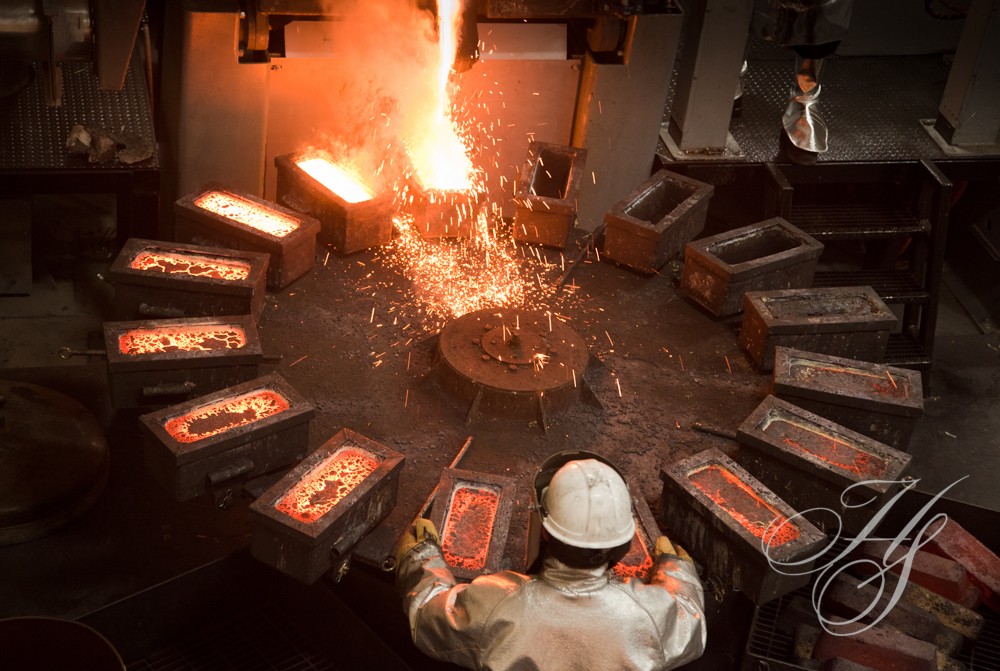 A man in white shirt and hard hat near fire.