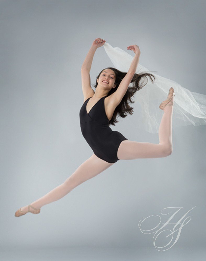 A woman in black leotard jumping with white cloth.