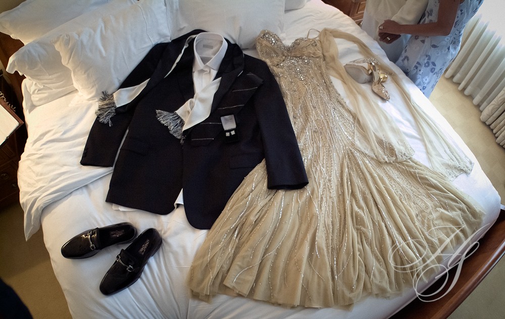 A couple of dresses and shoes on top of a bed.