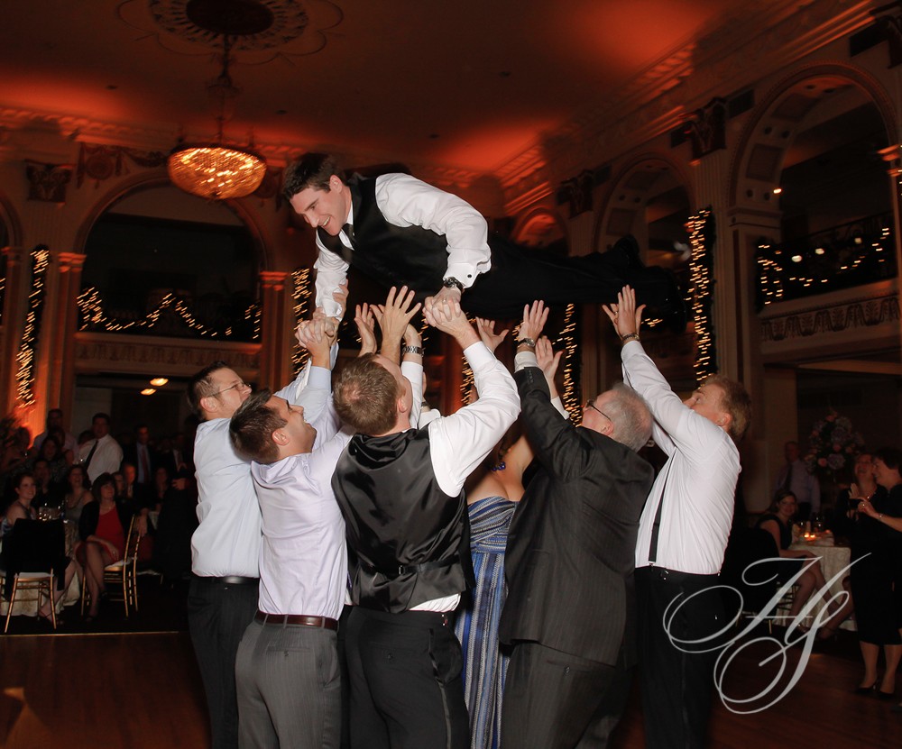 A group of men in suits and ties are jumping up into the air.