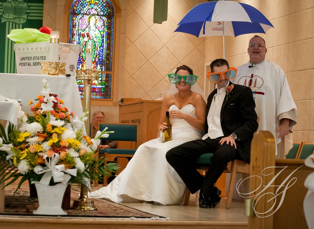 A bride and groom sitting on the floor with an umbrella over them.