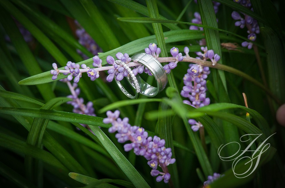 A wedding ring sitting on top of purple flowers.