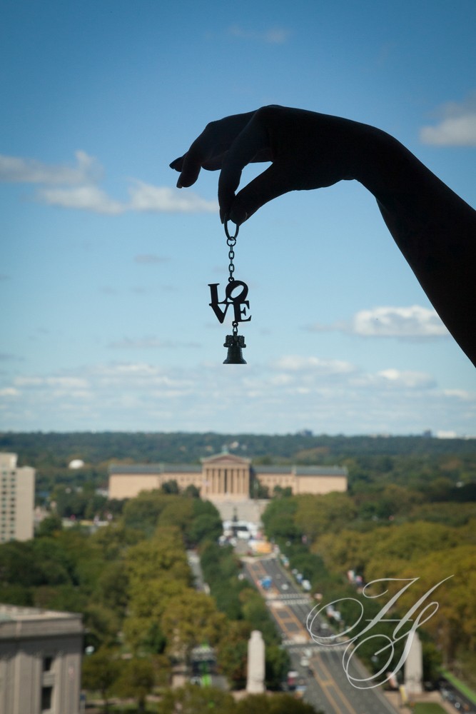 A person holding up a key chain with the word love on it.