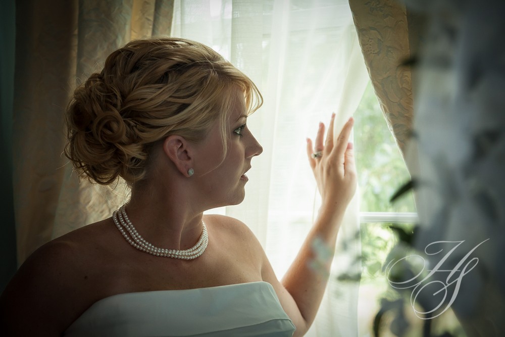 A woman in white dress looking out of window.