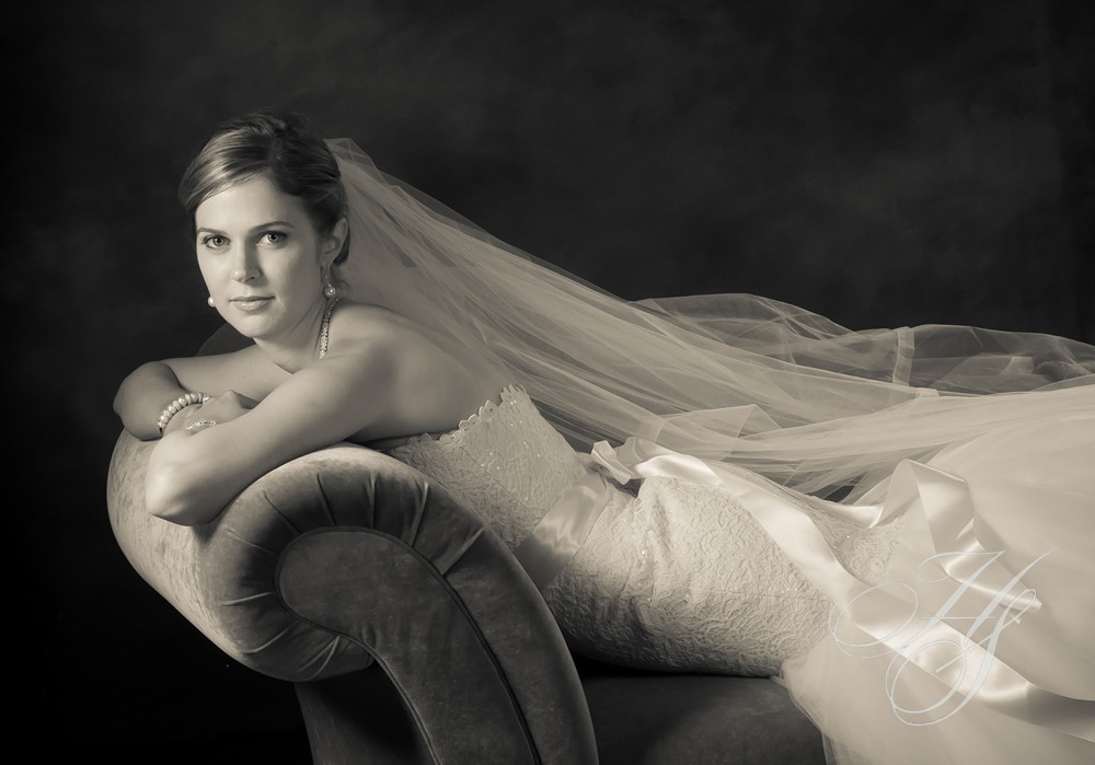 A woman in wedding dress laying on the back of a couch.