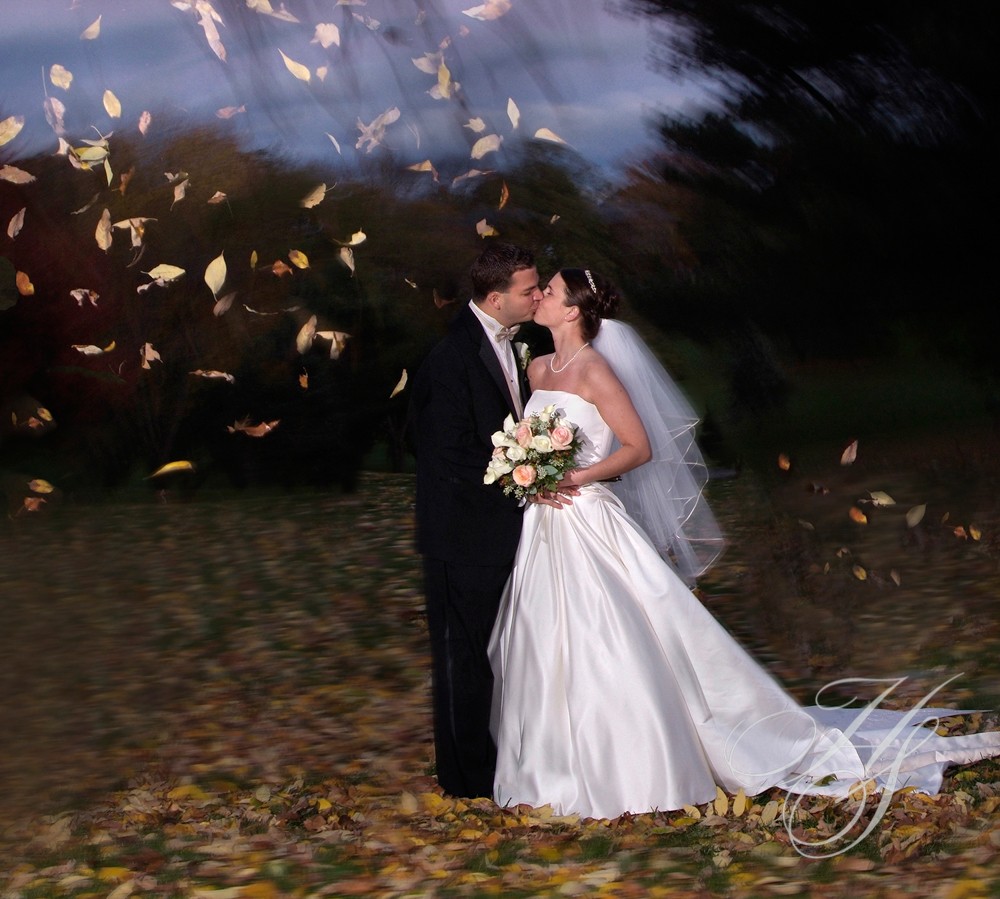 A bride and groom kissing in the leaves