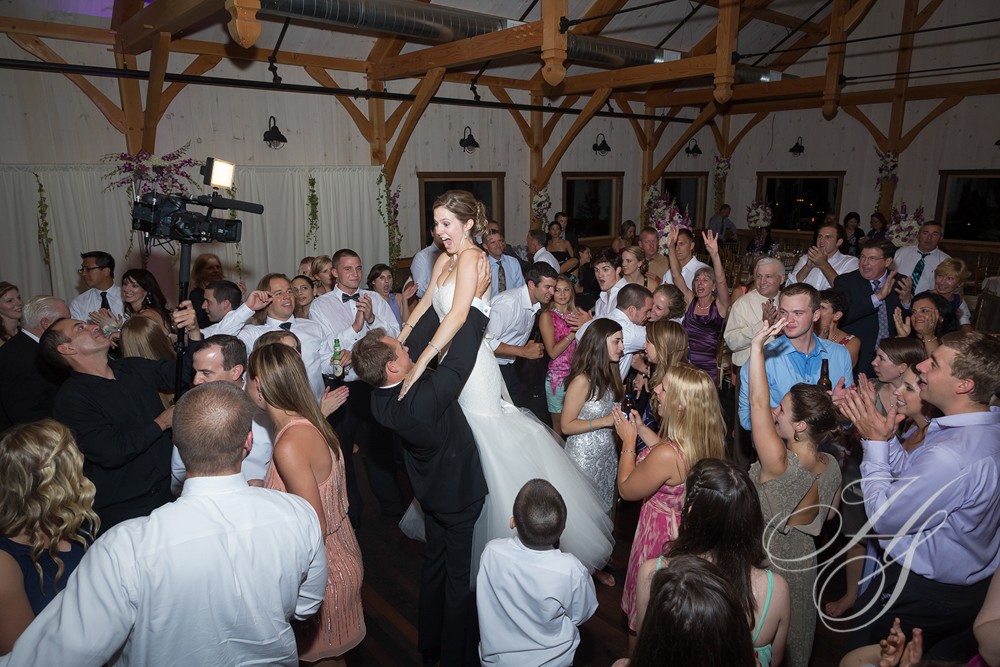 A bride and groom are being lifted by their feet.