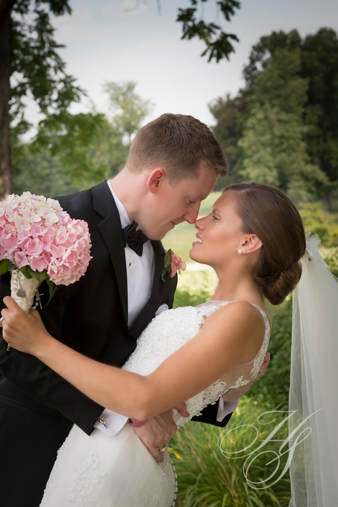 A bride and groom kissing in front of trees.