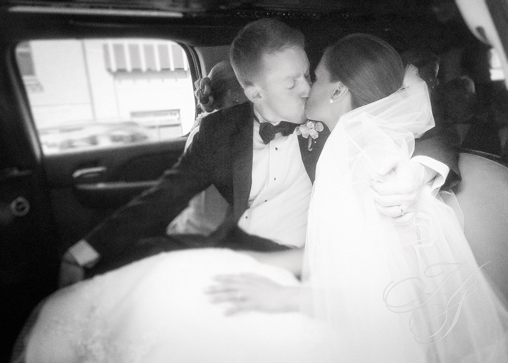 A couple kissing in the back of a car.