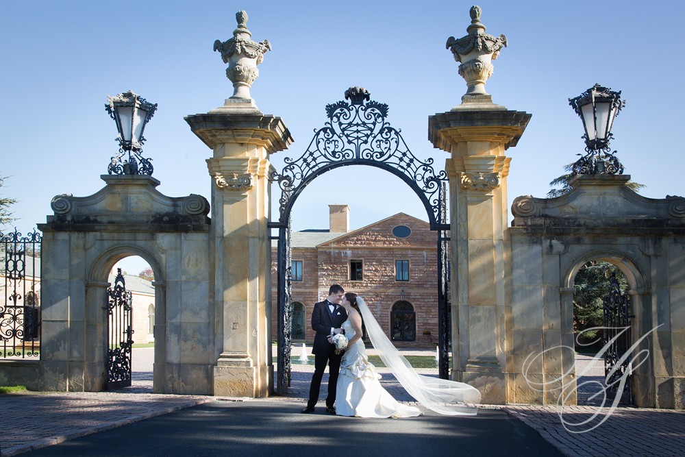 A bride and groom standing in front of an archway.