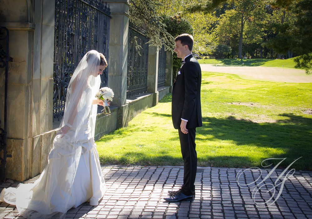 A bride and groom stand on the sidewalk.