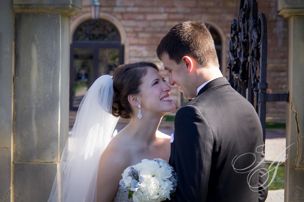 A bride and groom kissing in front of an arch.