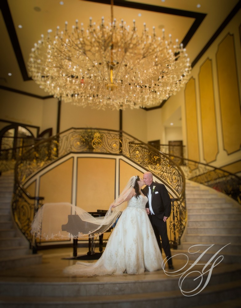 A bride and groom pose for a picture in front of the staircase.