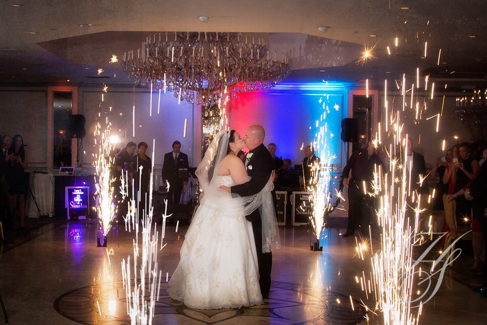A bride and groom dance in front of fireworks.