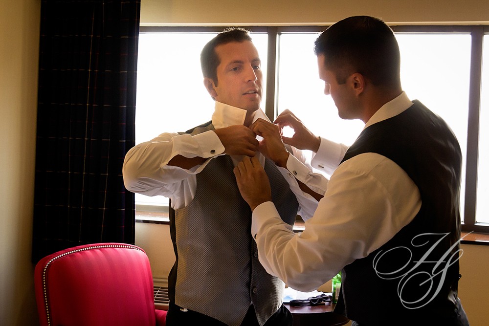 A man helping another man put on his tie.