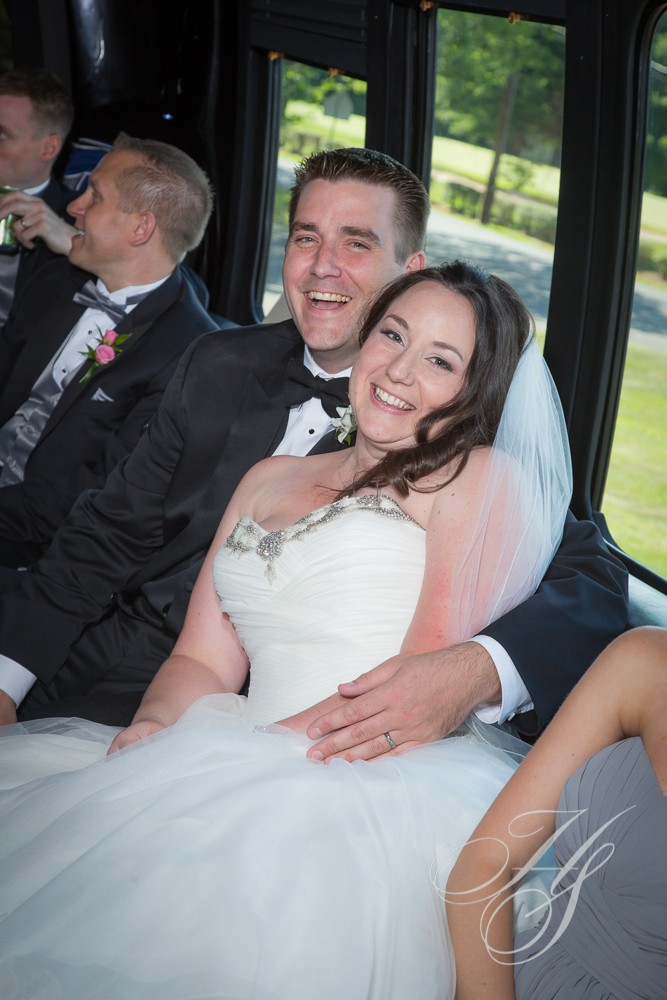 A bride and groom sitting on the back of a bus.