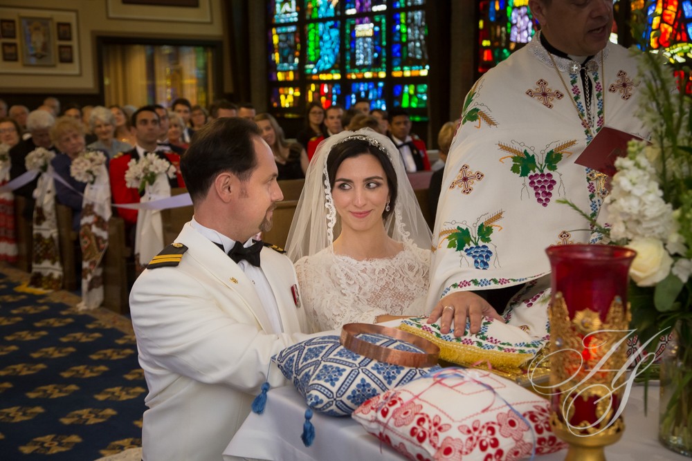 A bride and groom at the altar in front of stained glass windows.