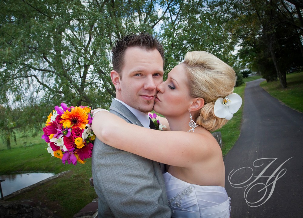 A bride and groom kissing in front of trees.