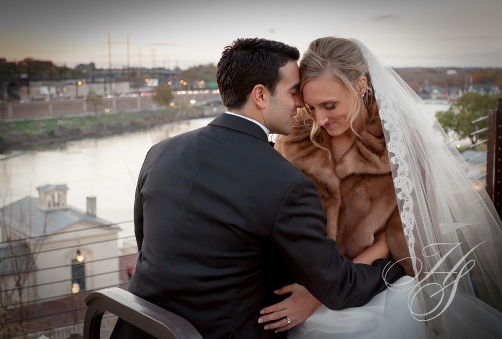 A bride and groom sitting on the ledge of a building.