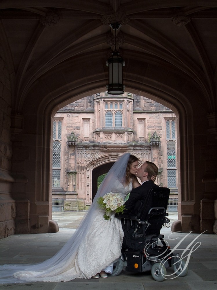 A bride and groom kissing in front of an archway.