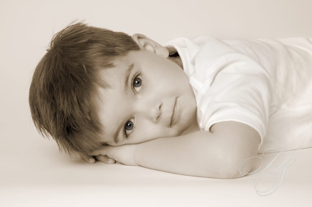A young boy laying on the ground with his head resting on his arms.